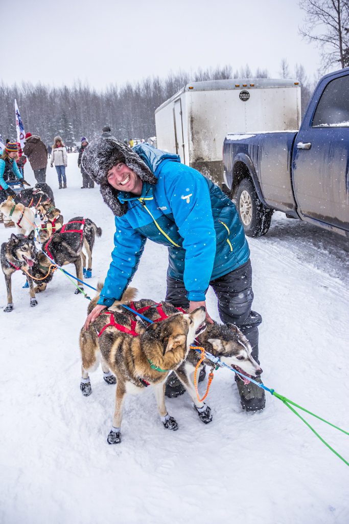 Travis at the finish of the Ceremonial start of the 2018 Iditarod. Here he is loving on Blue and her aunt Gremlin.