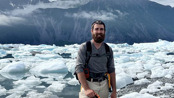 Nate Grandchamp in front of icebergs at Bear Glacier lagoon. Nate is a guide at Turning Heads Kennel.