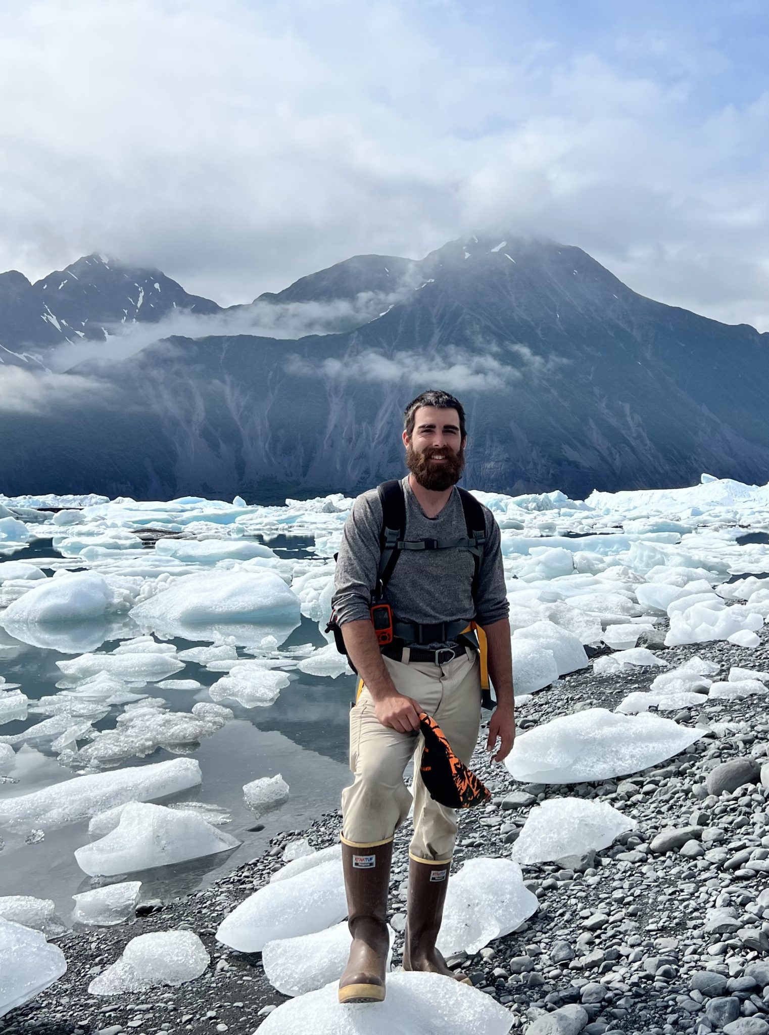 Nate Grandchamp in front of icebergs at Bear Glacier lagoon. Nate is a guide at Turning Heads Kennel.